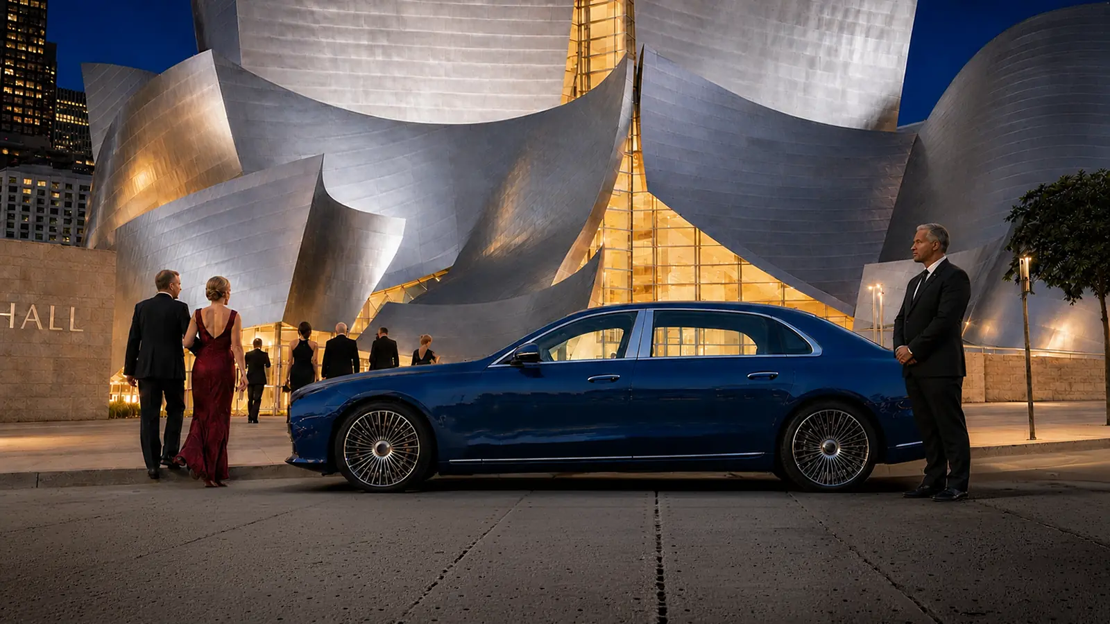 Private driver waiting beside a blue sedan as guests enter a concert venue in Los Angeles.