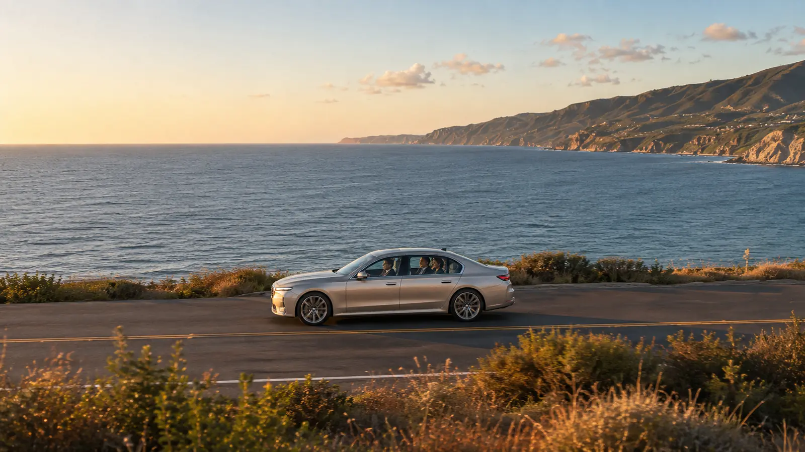 Private driver transporting clients in their own silver sedan along a scenic coastal highway.
