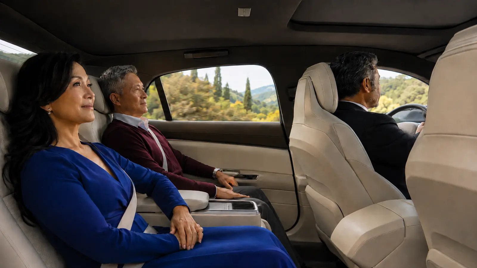 Asian couple relaxing comfortably in the back seat while a private driver handles the daytime trip.